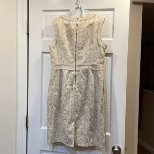 Dress is sleeveless, cream background with gold flower patten.Faux belt look